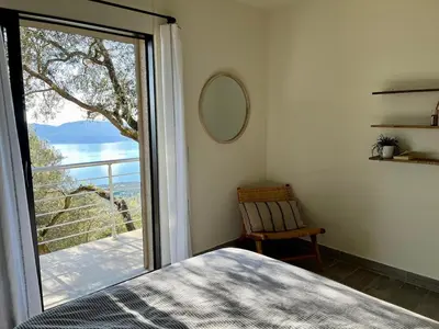 a bedroom with a bed and a sliding glass door at Maison avec vue imprenable in Olmeto