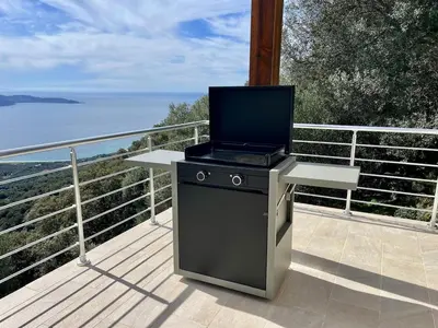 a grill on a balcony with a view of the ocean at Maison avec vue imprenable in Olmeto