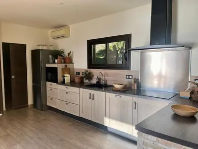 a kitchen with white cabinets and a black refrigerator at Maison avec vue imprenable in Olmeto