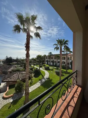 a balcony with a view of a resort with palm trees at Appartement T2 vue mer, piscine Linguizzetta Bravone in Linguizzetta