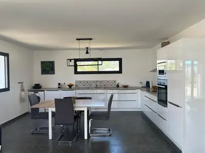 a kitchen with white cabinets and a table with chairs at Villa avec piscine privée Santa Maria Poggio in Santa-Maria-Poggio