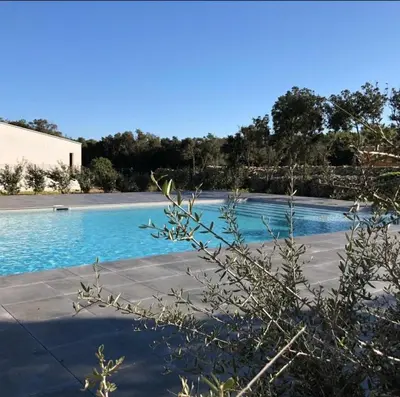 a swimming pool with blue water next to a building at A LAVANDA Maison BONIFACIO in Bonifacio