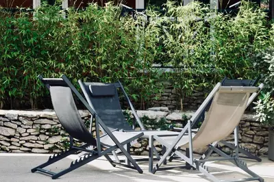 three lawn chairs sitting next to a stone wall at Résidence L'araguina in Bonifacio
