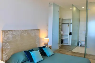 a bedroom with a large bed with blue pillows at Loft Centre-Ville Vue Mer in Porto-Vecchio
