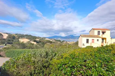 a white house on a hill with mountains in the background at Beautiful T2 in residence with swimming pools in Grosseto-Prugna