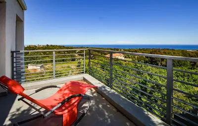 a red chair on a balcony with the ocean in the background at 2 Bedroom Lovely Home In Cervione in Cervione