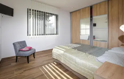 a bedroom with a bed and a chair and a window at 2 Bedroom Lovely Home In Cervione in Cervione