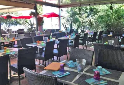 an outdoor restaurant with tables and chairs and umbrellas at Les Marines de Moriani in San-Nicolao