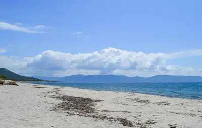 a sandy beach with the ocean and mountains in the background at Gorgeous Stacaravan In Casalabriva in Casalabriva