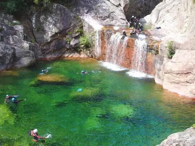 a group of people swimming in a waterfall at U Paesu in Zonza
