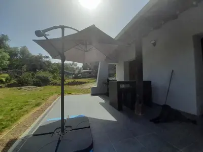 a large umbrella on the patio of a house at Maison de campagne idéale pour séjour en famille in Porto-Vecchio