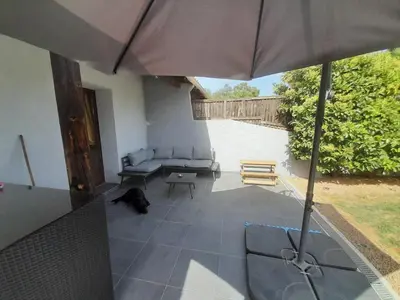 a dog laying on a patio with an umbrella at Maison de campagne idéale pour séjour en famille in Porto-Vecchio