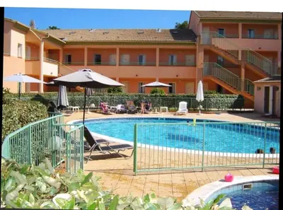 a swimming pool with an umbrella and a hotel at Appartement avec piscine in Linguizzetta