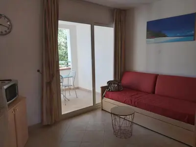 a living room with a red couch and a sliding glass door at Appartement avec piscine in Linguizzetta