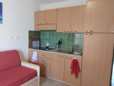 a kitchen with wooden cabinets and a sink and a red couch at Appartement avec piscine in Linguizzetta