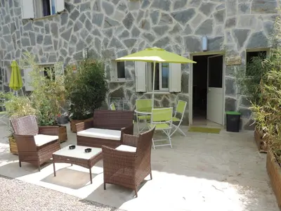 a patio with a table and chairs and an umbrella at Maquis et Mer in Sollacaro