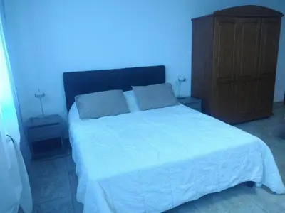 a bedroom with a white bed and a wooden cabinet at Maquis et Mer in Sollacaro