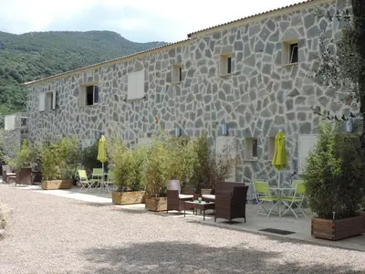 a stone building with chairs and tables and plants at Maquis et Mer in Sollacaro