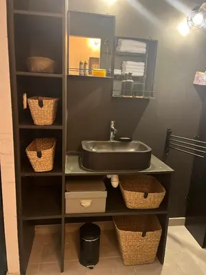 a bathroom with a sink and baskets on a shelf at Bas de Villa indépendant San Benedetto in Alata