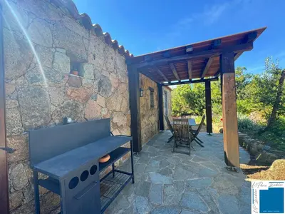 a patio with a grill and a stone wall at A Sérénità - Bergerie - Piscine Privée in Porto-Vecchio