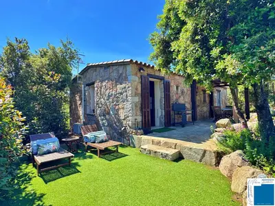a small stone house with a yard with benches at A Sérénità - Bergerie - Piscine Privée in Porto-Vecchio
