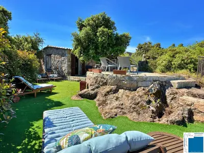 a yard with a stone retaining wall and a bench at A Sérénità - Bergerie - Piscine Privée in Porto-Vecchio