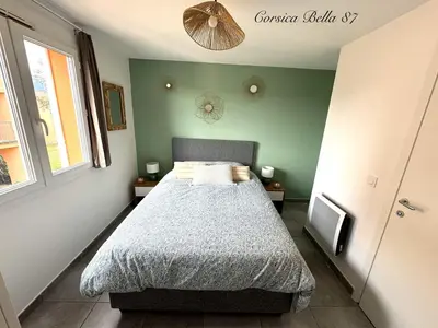 a bedroom with a bed and a green wall at Corsica Bella 87 T2 Cosy piscines proche plage in Lecci