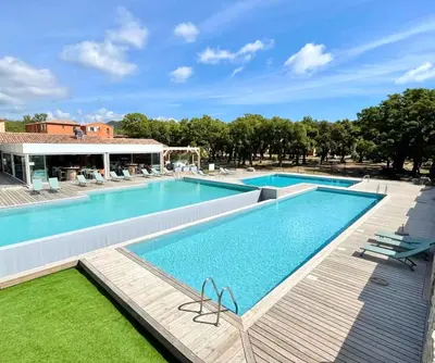 a large swimming pool with a wooden walkway around it at Corsica Bella 87 T2 Cosy piscines proche plage in Lecci