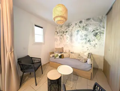 a small bedroom with a bed and a table and chairs at Appartement cosy Vue Mer et Montagne in Sari Solenzara