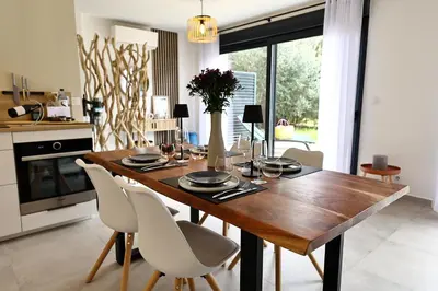 a wooden table in a kitchen with white chairs at U Sognu - Superbe T3 à Bonifacio classé 4 étoiles in Bonifacio