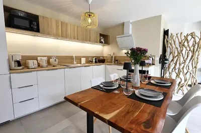 a kitchen with a wooden table and white cabinets at U Sognu - Superbe T3 à Bonifacio classé 4 étoiles in Bonifacio