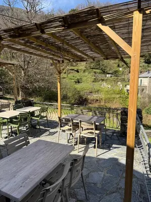 a group of tables and chairs under a wooden pergola at Gite d'étape Auberge Luna Piena in Santa-Reparata-di-Moriani