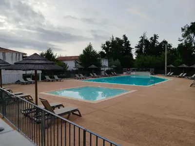 a large swimming pool with chairs and an umbrella at Appartement avec jardin piscine et plage 100 m in Poggio-Mezzana
