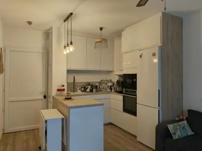 a kitchen with white cabinets and a white refrigerator at Appartement avec jardin piscine et plage 100 m in Poggio-Mezzana
