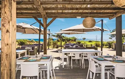 a restaurant with tables and chairs and umbrellas at Appartement avec jardin piscine et plage 100 m in Poggio-Mezzana