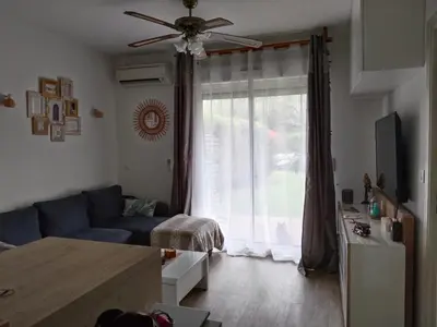 a living room with a blue couch and a window at Appartement avec jardin piscine et plage 100 m in Poggio-Mezzana