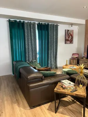 a living room with a leather couch and green curtains at Villa avec piscine in Alata