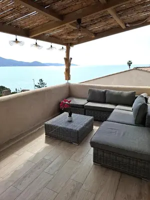 a patio with couches and a view of the ocean at Appartement vue mer à 1min de la plage in Grosseto-Prugna
