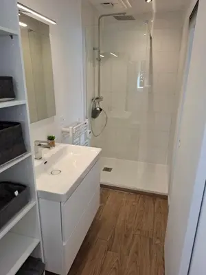 a white bathroom with a shower and a sink at Appartement vue mer à 1min de la plage in Grosseto-Prugna
