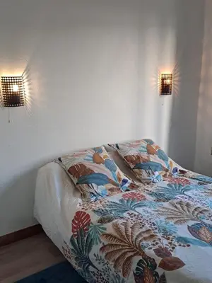 a bed in a bedroom with two lights on the wall at Appartement T2 in Pietrosella
