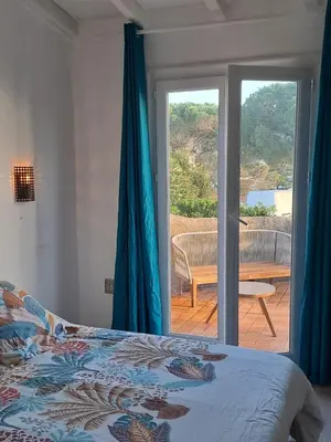 a bedroom with a bed and a sliding glass door at Appartement T2 in Pietrosella