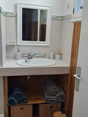 a bathroom with a sink and a mirror and towels at Appartement T2 in Pietrosella