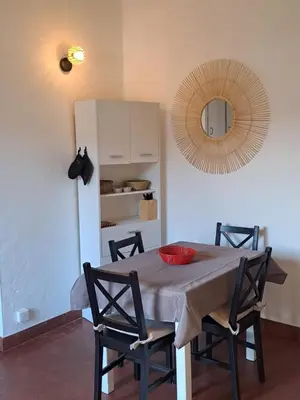a dining room with a table with chairs and a mirror at Appartement T2 in Pietrosella