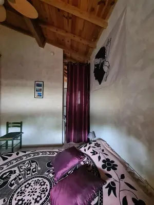 a bedroom with a bed with purple pillows at Casa Ghjadda - gite ombragé avec accès piscine - in Appietto