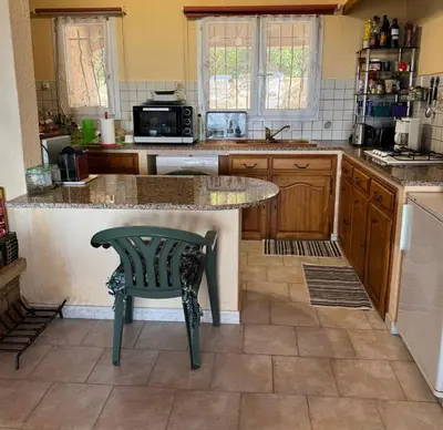 a kitchen with a counter and a table and a chair at Domaine Mare e Monti - T2 Les Mimosas in Albitreccia
