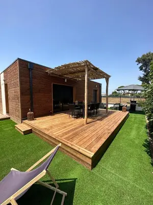a wooden deck with a pergola in a yard at Casa Juliette Maison bois in Aléria