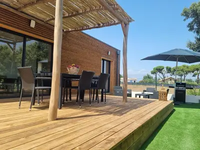a wooden deck with a table and chairs and an umbrella at Casa Juliette Maison bois in Aléria