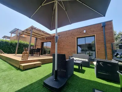 a patio with an umbrella on the grass at Casa Juliette Maison bois in Aléria