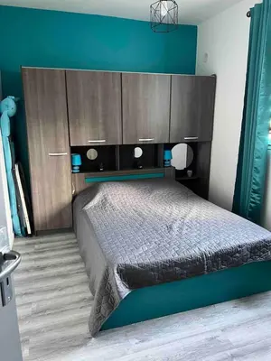 a bedroom with a large bed with a blue wall at Le petit mauricia in San-Nicolao