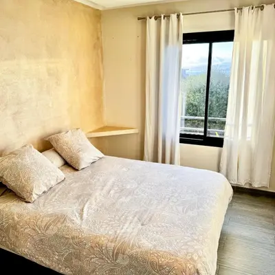 a bedroom with a bed with two pillows and a window at Appartemment vue mer 50m2 in Propriano
